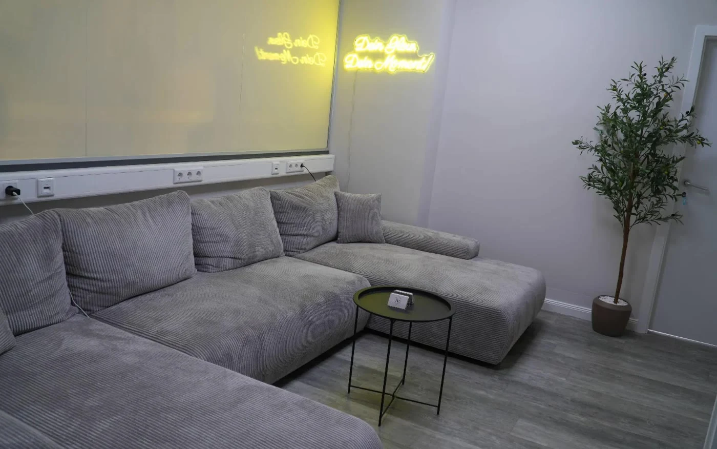Die Lounge mit gemütlichem Sofa und Neon-Schriftzug